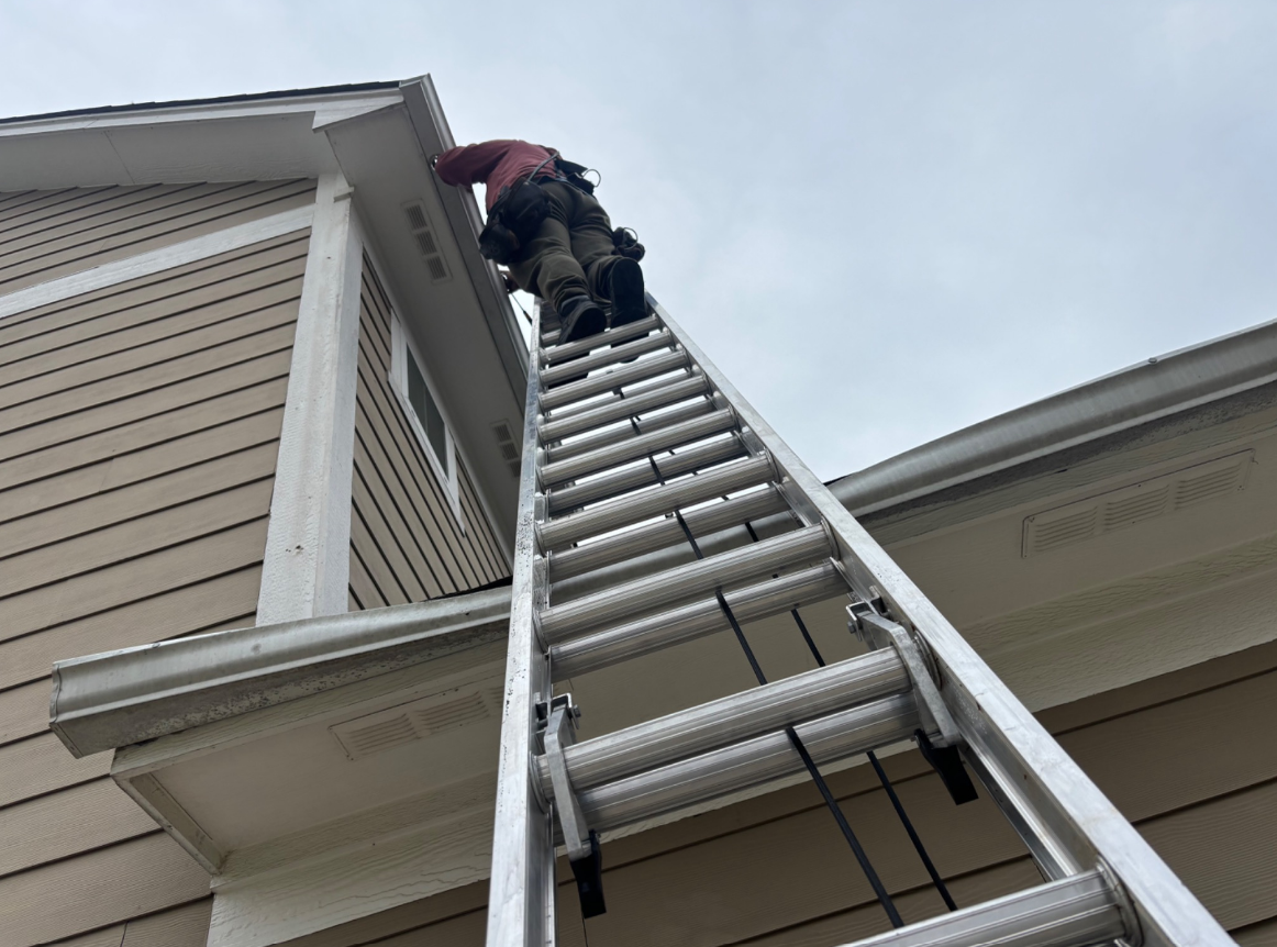 Steven installing seamless gutters on a ladder in Indianapolis